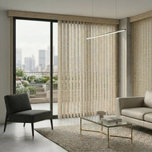 Load image into Gallery viewer, Signature Collection Fabric Vertical Blinds in Beige harmonize with the room's neutral tones, subtly framing a stunning city skyline view while a gray couch and black chair provide sophisticated contrast.
