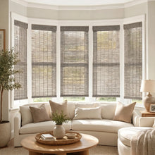 Load image into Gallery viewer, Warm up your space with Cordless Woven Wood Shades, expertly crafted to filter soft beige light into a serene room setting, complete with natural accents and plush furnishings.