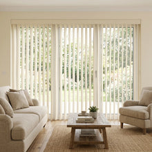 Load image into Gallery viewer, Woodtone Faux Wood PVC Vertical Blinds perfectly complement the beige tone, allowing natural light to illuminate this calm and inviting room with rich wood accents.