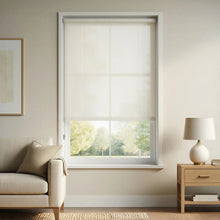Load image into Gallery viewer, Warm White Sandstone Beige Signature solar roller shades in a cozy living room nook, showcasing the 3% mesh fabric that blocks 97% of harmful UV rays while preserving the outdoor view.