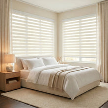 Load image into Gallery viewer, Zebra Light Filtering Roller Shades add a touch of elegance to this serene bedroom, filtering natural light and enhancing creamy white bedding.