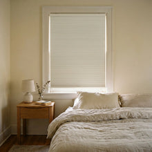 Load image into Gallery viewer, Sunlight hits the Creamy White (White Dove) 9 16 Inch Classic Single Cell Blackout Cordless Shades in this modern bedroom, creating a serene, light-free setting.