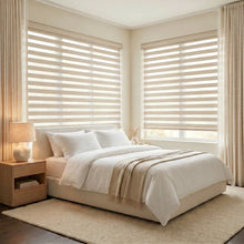 Load image into Gallery viewer, Zebra Light Filtering Roller Shades filter natural light, creating a peaceful atmosphere in this serene bedroom with creamy white tones and minimal decor.