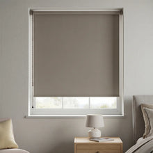 Load image into Gallery viewer, Main front view of a Taupe Signature blackout roller shade providing total light blockage in a modern bedroom.