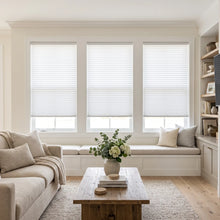 Load image into Gallery viewer, Simplistic Cordless Pleated Shades in pure white harmonize with the room's serene atmosphere, allowing natural light to filter through while maintaining a sense of calm, amidst a stylish arrangement of furniture and decorative accents.