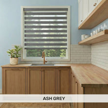 Load image into Gallery viewer, Ash Grey Zebra Solar Roller Shades in a kitchen with wooden cabinets.
