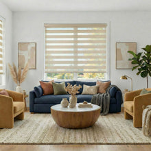 Load image into Gallery viewer, Beige Zebra Solar Roller Shades in a cozy living room with a blue sofa, yellow armchairs, and a wooden coffee table.
