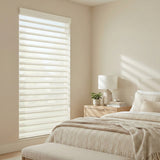 Light diffusing sheer shades elegantly scattering light in a clean natural toned bedroom.