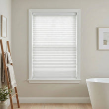 Load image into Gallery viewer, Window with white pleated shades in a bathroom setting with a bathtub and towel rack.
