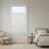 Modern bedroom with a window featuring white pleated shades with top-down-bottom-up functionality, a bed, and a chair.