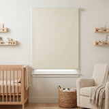 Classic Blackout Vinyl Roller Shades adorn a serene nursery, softly filtering beige-hued light and creating a cozy atmosphere.