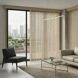 Signature Collection Fabric Vertical Blinds in Beige harmonize with the room's neutral tones, subtly framing a stunning city skyline view while a gray couch and black chair provide sophisticated contrast.
