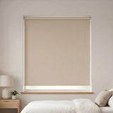 Economy Basic Vinyl Blackout Roller Shades in a cozy bedroom setting, providing a neutral beige backdrop and blocking out light for a peaceful atmosphere.