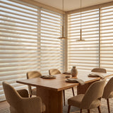 Dining room with wooden table and chairs, large windows with light dimming sheer shades and a pendant light.