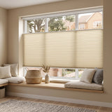 Simplistic Cordless Tdbu Pleated Shades effortlessly harmonize with beige tones, illuminating a warm and inviting atmosphere in this elegant room with white walls and wooden floors.