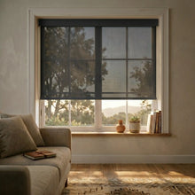 Load image into Gallery viewer, Sleek Black Signature solar roller shades with 5% openness, styled in a luxury living room to dramatically reduce screen glare while preserving a view of the garden.
