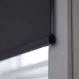 Extreme macro close-up of the black fabric-wrapped hem bar on a ProGrade blackout roller shade, showing the premium finish.