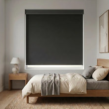 Load image into Gallery viewer, Modern Fabric Blackout Roller Shades provide sleek, light-blocking coverage for this modern bedroom's large window, complementing white walls and wooden flooring.
