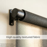 Macro close-up of a black Signature solar roller shade highlighting the high-quality fabric texture and smooth roller mechanism.