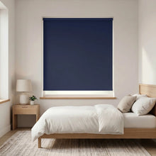 Load image into Gallery viewer, Economy Basic Vinyl Blackout Roller Shades in a bedroom setting, creating a serene and intimate atmosphere with smooth, blue-toned light filtering through.

