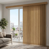 Warm Woodtone Faux Wood PVC Vertical Blinds beautifully complement the brown shade of this sliding glass door, inviting outdoor living into a cozy gray couch-filled room.