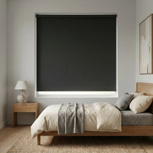 Load image into Gallery viewer, Modern Fabric Blackout Roller Shades provide sleek, light-blocking coverage for this modern bedroom's large window, complementing white walls and wooden flooring.
