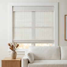 Load image into Gallery viewer, Enhance the serene ambiance of your space with Cordless Woven Wood Shades, seamlessly integrating into the calming cream-toned backdrop, while softly filtering natural light through partially open white blinds.
