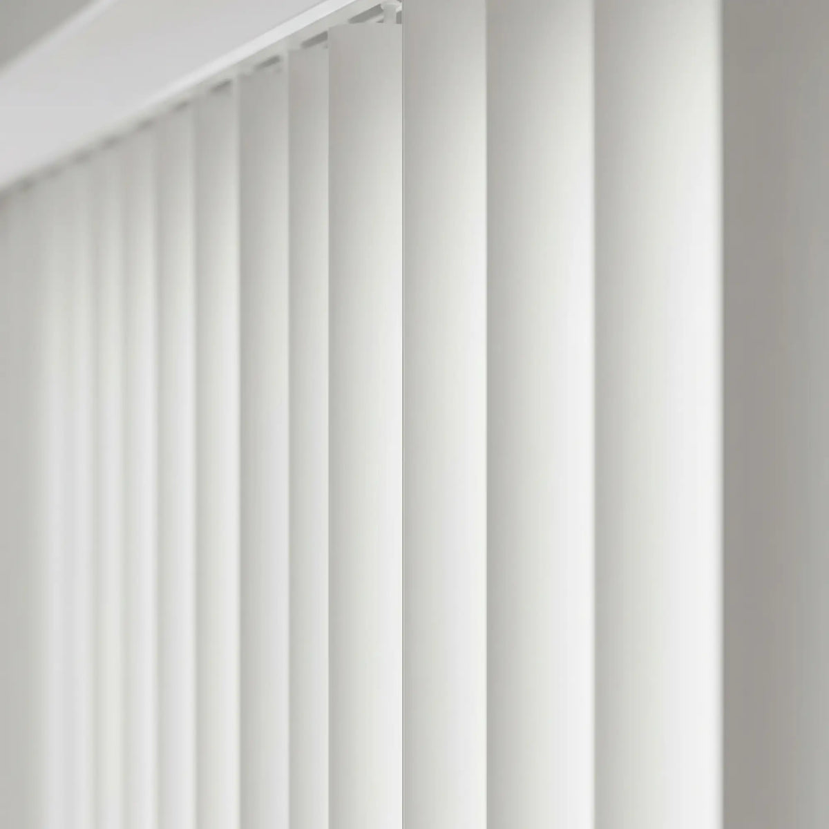 View of a serene living room with Cream Premier Pvc Vertical Blinds, ideal for expansive windows requiring versatile light management.