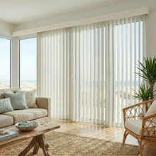 Load image into Gallery viewer, Custom window treatments: Creamy (Belize White Sand) 3 1/2 Inch Signature Pvc Vertical Blinds shown in a inviting living room, filtering incoming daylight effectively across wide glass surfaces.
