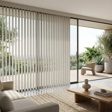 Load image into Gallery viewer, Natural sunlight hits the Creamy 3 1/2 Inch S Shape Pvc Vertical Blinds in a cozy retreat, providing elegant, wave-like window coverage.
