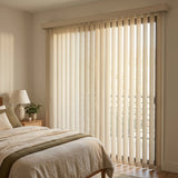 Signature Collection Fabric Vertical Blinds in creamy white provide subtle texture and light filtering for this serene bedroom, featuring a soothing green blanket against a glass door wall.