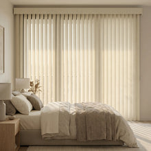 Load image into Gallery viewer, Softly filtering natural light, Signature Collection Fabric Vertical Blinds in creamy white complement the beige comforter and warm wooden nightstand in this serene bedroom sanctuary.
