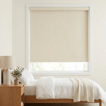 Load image into Gallery viewer, Classic Fabric Blackout Roller Shades in creamy white create a peaceful atmosphere for restful sleep in this serene bedroom with beige accents and natural light.
