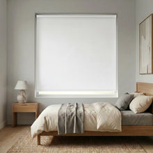 Load image into Gallery viewer, Modern Fabric Blackout Roller Shades in creamy white add sophistication and light blocking functionality to this minimalist bedroom, perfect for a restful retreat.
