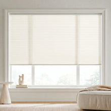 Load image into Gallery viewer, A look at Creamy White (Snow White) 7 16 Inch Double Cell Light Filtering Shades inside a bright living room, beautifully diffusing natural sunlight.
