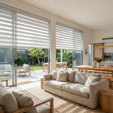 Modern living space features Zebra Solar Roller Shades in creamy white, blocking UV rays and flooding rooms with natural light.