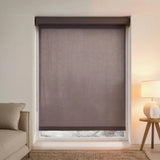 Close-up of dark brown Chocolate light filtering roller shades installed in a cozy bedroom with warm lighting.
