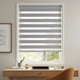 Elegant gray and white striped Zebra Room Darkening Roller Shades adorn this cozy living space, perfect for working or relaxing.