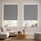 Classic Blackout Vinyl Roller Shades in a modern living room, evoking a cozy atmosphere with gray tones and dimmed light.