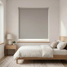 Load image into Gallery viewer, Economy Basic Vinyl Blackout Roller Shades in a cozy gray bedroom setting, providing discreet light dimming for a restful atmosphere.


