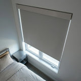 Gray ProGrade blackout roller shade seen from a bedside perspective, ideal for sleep optimization and privacy.