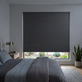 Gray Raindance Signature Blackout Double Cellular Shade on a bedroom window beside a wood nightstand