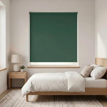 Load image into Gallery viewer, Economy Basic Vinyl Blackout Roller Shades in a serene bedroom setting, where soft green hues evoke calmness and tranquility, while these versatile shades seamlessly block out light, ensuring a restful atmosphere.
