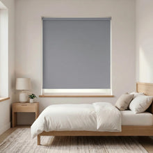 Load image into Gallery viewer, Economy Basic Vinyl Blackout Roller Shades in a sleek room, softly dimming natural light and creating a cozy ambiance.

