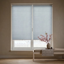 Load image into Gallery viewer, Custom window treatments: Light Blue (Hazy) 3 8 Inch Budget Single Cell Light Filtering Cordless Shades shown in a modern living room, allowing bright, diffused daylight to fill the interior.
