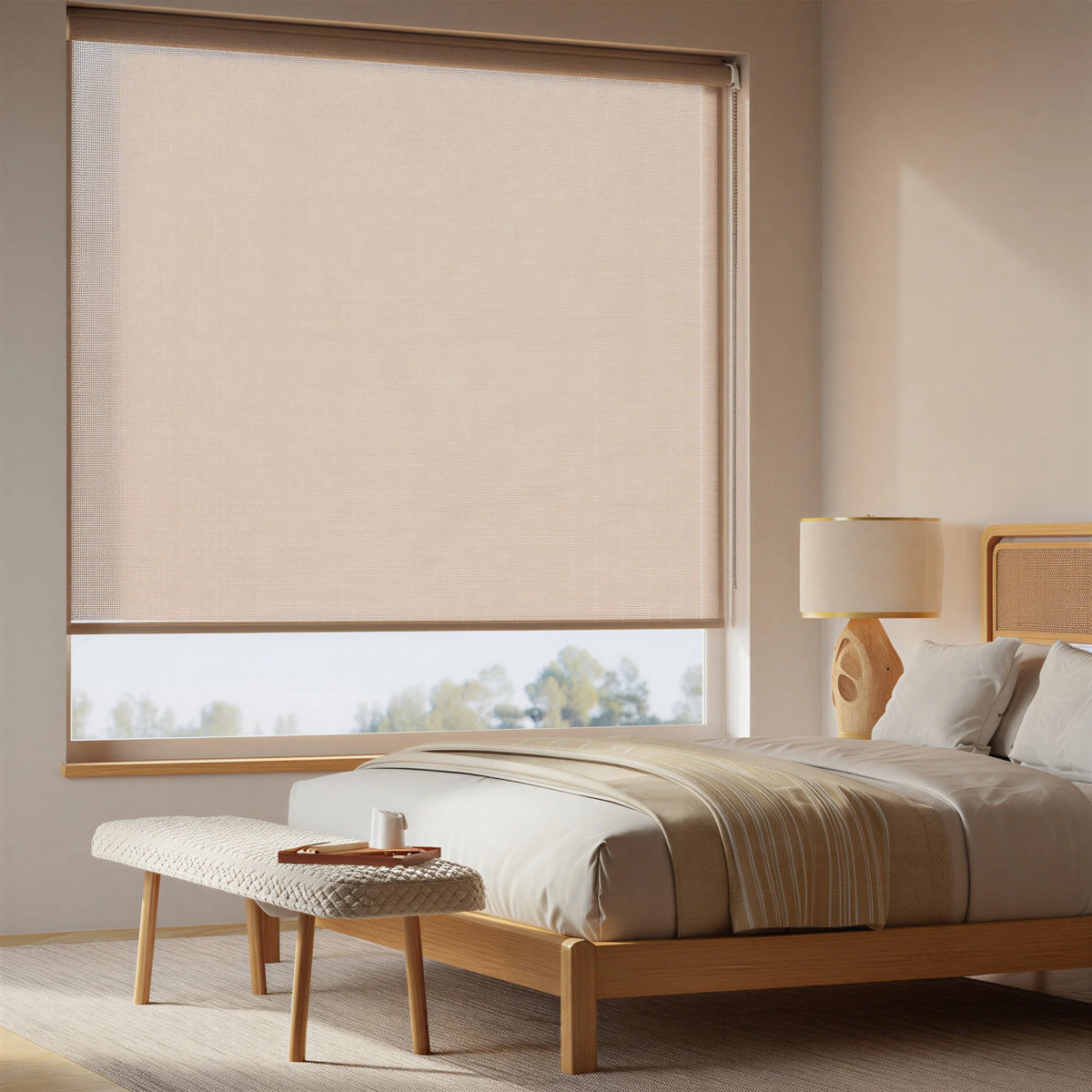 Light tan Flaxen Luxe natural light filtering roller shades in a cozy bedroom with warm wood accents.