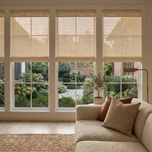 Load image into Gallery viewer, Beeswax Natural Bamboo Shades in soft tan overlooking a garden courtyard
