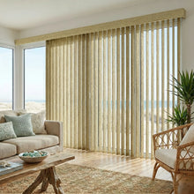 Load image into Gallery viewer, Natural sunlight hits the Taupe (Belize Brownstone) Signature Pvc Vertical Blinds in this inviting living space, delivering sleek functionality and room-darkening capabilities.
