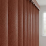 Woodtone Faux Wood PVC Vertical Blinds in Taupe subtly complement a plush sectional sofa, creating a warm and inviting living room ambiance.
