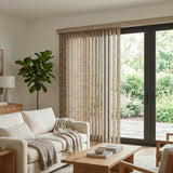 Signature Collection Fabric Vertical Blinds in Warm Brown add understated elegance to this inviting living room, where a brown window shade complements the soft gray blanket and plush white couch.